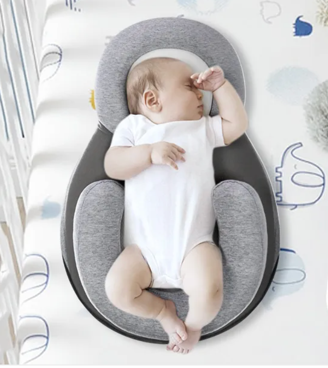Baby lying in a gray and white baby nest with text about its design and safety features.